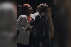 Duas mulheres, uma com cabelo ruivo e outra com cabelo longo, em um ambiente escuro, possivelmente em uma festa ou evento.