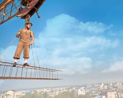 Gambar young man in construction worker attire, looking determined with a cityscape in the background