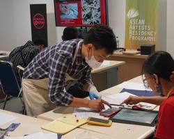 Cambodian artisans carefully working on a traditional woodblock print.