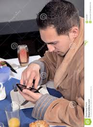 Closeup view of a man dressed in a dressing gown using his mobile at breakfast scrolling with his finger on the touchscreen. MR: YES; PR: NO - man-using-his-mobile-breakfast-closeup-view-dressed-dressing-gown-scrolling-finger-touchscreen-34582867