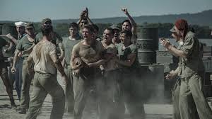 A promotional still from The Mosquito Bowl showing actors Nicholas Galitzine and Bill Skarsgård in military uniforms on a football field.