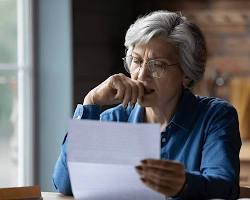 Image of confused elderly person looking at a pile of paperwork