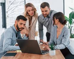 Image of group of business people working in an office, all using computers and connected to the internet