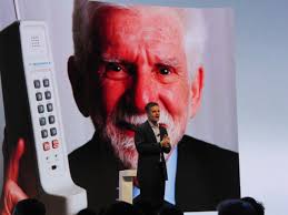 Motorola Mobility CEO Dennis Woodside talks to the press as the image of Martin Cooper, who led the Motorola team which invented the mobile phone in 1973, ... - motorola-mobility-ceo-dennis-woodside-and-marty-cooper-inventor-of-mobile-phone