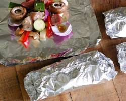 Изображение: Meat and vegetables wrapped in aluminum foil and cooking on a grill