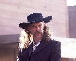 Image of Wild Bill Hickok, a legendary figure of the American West, with his signature long hair and mustache, wearing a buckskin jacket and a widebrimmed hat