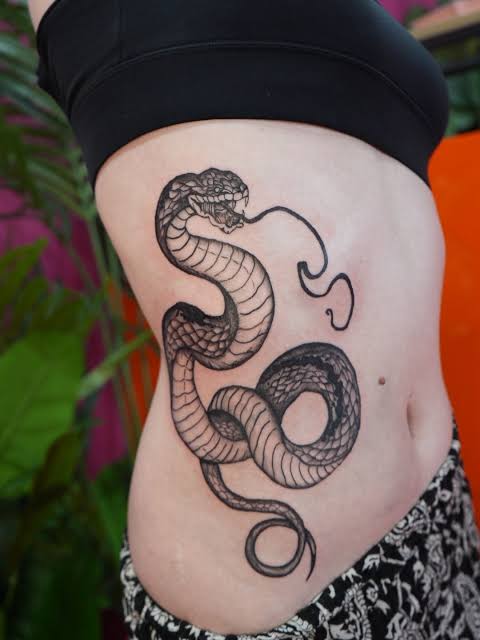 A bold black ink tattoo of a coiled snake with its mouth open and ...