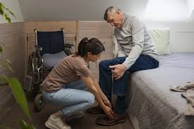 caregiver assisting an elderly man with putting on shoes during a morning routine