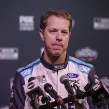 Brad Keselowski standing next to his race car in the pit lane.