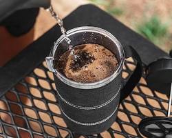Image of person enjoying a cup of coffee brewed from a portable French press while outdoors