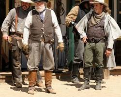 Image of dramatic reenactment of a Wild West gunfight, with two men facing each other, guns drawn, in a dusty street