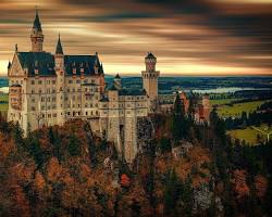 Imagen de El Castillo de Neuschwanstein, un castillo romántico de cuento de hadas con torres y torretas que se alzan sobre un paisaje alpino.