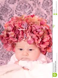 La neonata appena nata che portano un cappello floreale dentellare ed il damasco wallpaper la priorità bassa. MR: YES; PR: NO - bambino-del-cappello-del-fiore-17917982