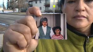 Reyna, mother of Moises Morales, holds a photo of her and her son when Moises was 8-years-old - image