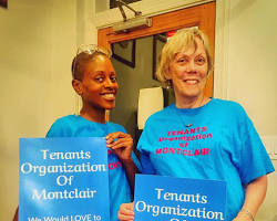 Image of someone holding a rent control sign, smiling