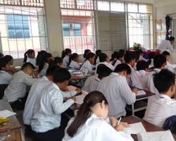 Cambodian students in a classroom raising their hands