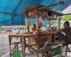 Gambar Angkringan in Solo, with people gathering around small tables, enjoying nasi kucing and various satay.