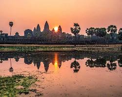 Image of Angkor Wat at sunrise, with its reflection shimmering in the surrounding moat