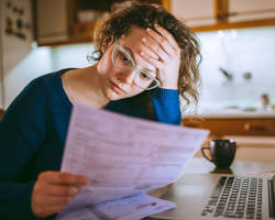 Image of person looking stressed while looking at their bank account