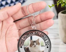 person holding a keychain with a pet photoの画像