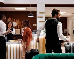 Gambar Bellboy helping a guest with their luggage at the hotel entrance
