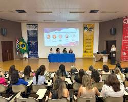 Imagem de Mulheres participando de um evento de empreendedorismo feminino, com o logo de um órgão governamental no fundo