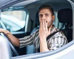 Image of person driving a car with a confused expression