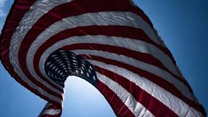 Low angle view of American flag waving against blue sky