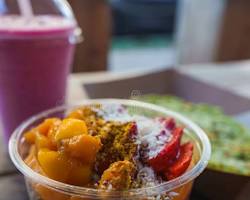 Acai bowl on a wooden table with blurred background of a cafe interiorの画像