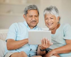 Изображение: elderly person using a video call app on a tablet to connect with their family and friends