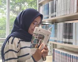 Gambar tumpukan buku tebal dengan seseorang yang tampak bingung memegang kepala