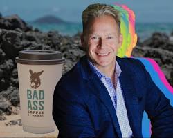 person holding a Hawaiian themed coffee cup with the ocean in the backgroundの画像