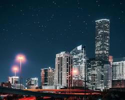 Image of person holding a phone with the Houston skyline in the background
