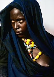 An Afar nomad woman from the Danakil Desert of Ethiopia wears amber jewelry and indigo dyed blue veils. She exudes a fierce beauty that reflects the ... - BF_ABG_020