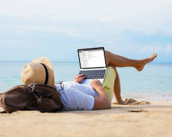 Image of someone relaxing on a beach with a laptop