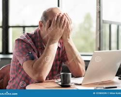 Image of person looking at a computer screen rubbing their eyes