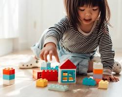 Imagen de children of different ages engaging in various activities: a baby playing with blocks, a toddler reading with an adult, and older children playing outside