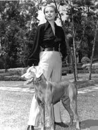 Grace Kelly in slacks and shirt with one of her dogs