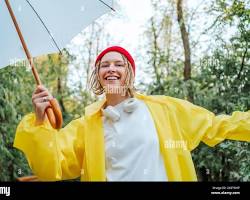 Image of someone wearing a raincoat and holding an umbrella, smiling
