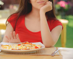 Image of person eating a plate of food and then pushing it away