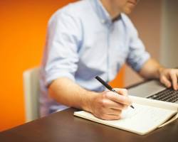 Image de Person Writing on a Laptop at a Desk