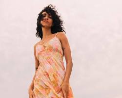 Image of girl in long flowy dress with colorful print on beach at sunset