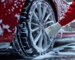 Image of car wheel being washed with a sponge and soap