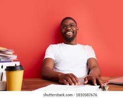 Image of person writing on a laptop and smiling, with a camera in the background