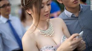 A bride checks her messages while getting ready for a group picture after a mass wedding outside a Chinese temple in Kuala Lumpur on December 12, 2012. - 130829180341-kuala-lumpur-bride-horizontal-gallery
