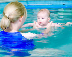 Image of mother and child swimming in a calm ocean, the child splashing with joy