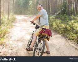 Image of person cycling through a forest road on a sunny day